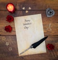 Vintage Valentine`s Day card with red roses, wooden decorations, red candle and ink and quill on vintage oak - top view